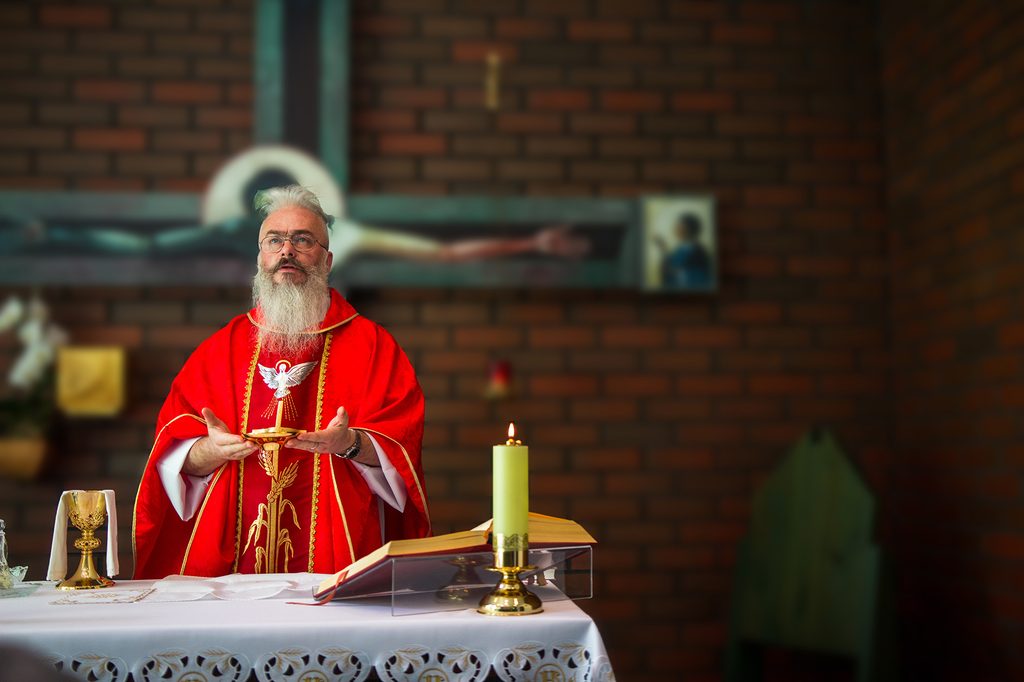 A priest in a red chasuble celebrating Holy Mass at the altar