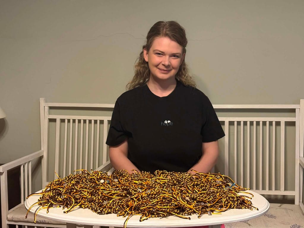 Natalia Tarnogrodzka przy stole pełnym różańców na rękę